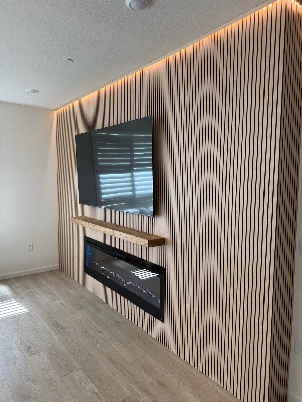 Wood slat accent wall with LED cove lighting, an electric fireplace and a floating mantel